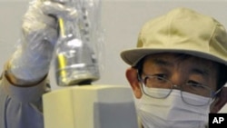 A staff member checks the level of radiation on an industrial product produced in Fukushima Prefecture at Fukushima Technology Center in Koriyama, northeastern Japan, April 4, 2011