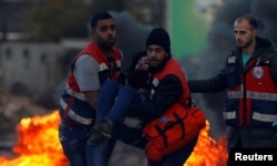 Medics evacuate a wounded Palestinian woman during clashes with Israeli troops near the Jewish settlement of Beit El, near Ramallah, in the Israeli-occupied West Bank December 13, 2018.