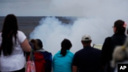 Visitors watch as steam and gas rise from Kilauea's summit crater in Volcanoes National Park, Hawaii, May 9, 2018.