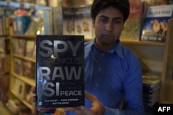 FILE - A Pakistani salesman shows "Spy Chronicles: RAW, ISI and the Illusion of Peace," co-written by Asad Durrani, a retired Pakistani army officer, at a bookstore in Islamabad, May 30, 2018.