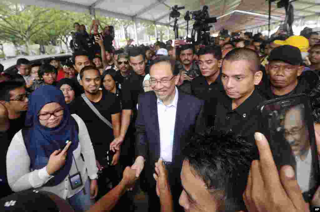 Malaysian opposition leader Anwar Ibrahim, center, is greeted by supporters as he leaves the court house after the first day of his final hearing in Putrajaya, Malaysia, Tuesday, Oct. 28, 2014. Malaysia's top court on Tuesday began hearing a final appeal