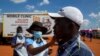 Un agent de santé vérifie la température d'un homme pour un dépistage et un test au COVID-19 à Lenasia South, sud de Johannesburg, Afrique du Sud, le mardi 21 avril 2020, lors d'une campagne visant à lutter contre la propagation du coronavirus. (Photo AP / Themba Hadebe)