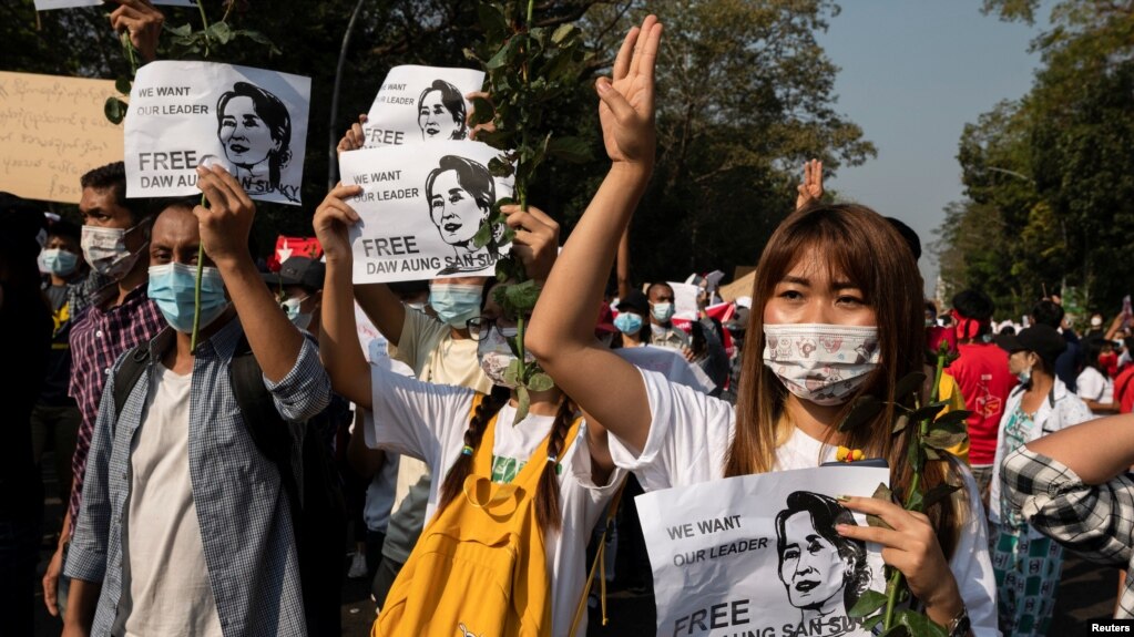 缅甸仰光的示威者致象征反政变抗议的三指礼，另一只手拿着缅甸国务资政昂山素季的画像，要求军政府释放这位诺贝尔和平奖得主。