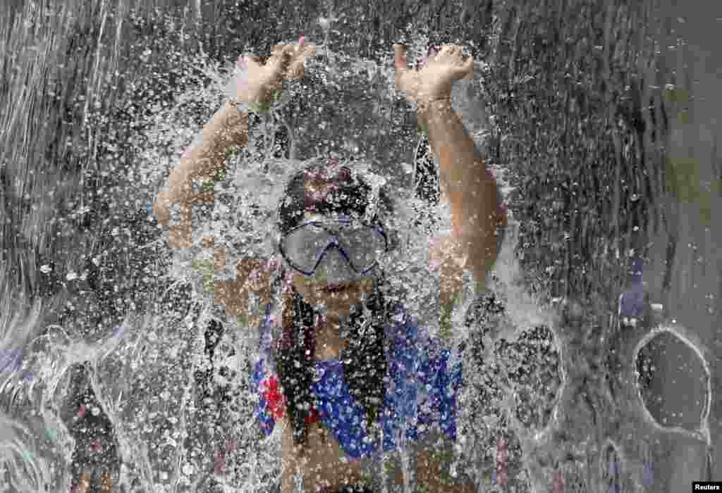 A girl plays under the waterfall at the fun bath in Endenich, a suburb of Bonn, western Germany.