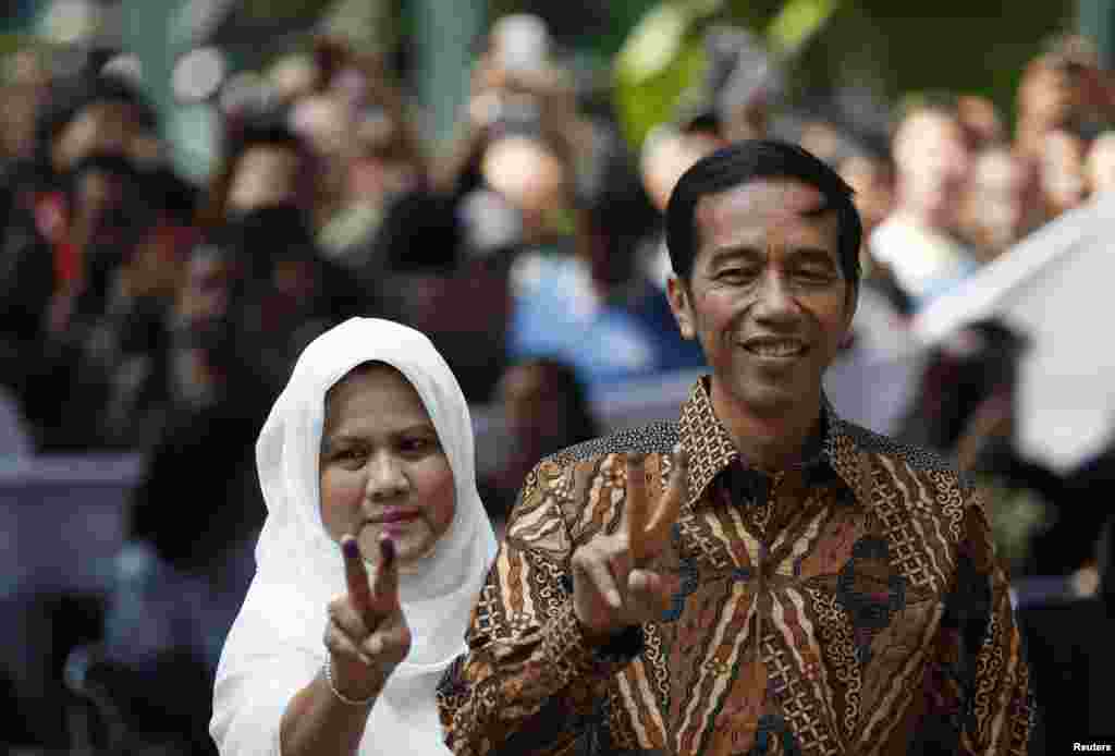 Kandidat presiden Joko &quot;Jokowi&quot; Widodo dan istri Iriana berpose setelah memberikan suara di Jakarta Pusat (9/7).&nbsp;(Reuters/Darren Whiteside)