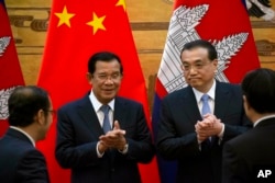 Cambodian Prime Minister Hun Sen, center left, applauds with Chinese Premier Li Keqiang during a signing ceremony at the Great Hall of the People in Beijing, China, Tuesday, Jan. 22, 2019. Hun Sen, making a four-day visit to China, said Tuesday that Beiji Cambodian Prime Minister Hun Sen, center left, applauds with Chinese Premier Li Keqiang during a signing ceremony at the Great Hall of the People in Beijing, China, Tuesday, Jan. 22, 2019.