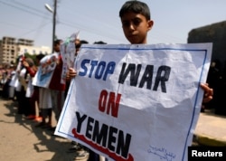 FILE - A boy holds a placard as he demonstrates outside the offices of the United Nations in Sanaa, Yemen, to denounce an airstrike that killed dozens including children in the northwestern province of Saada, Aug. 13, 2018.