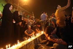 Iraqi women grieve as people light candles at the scene of a massive car bomb attack in Karada, a busy shopping district where people were shopping for the upcoming Eid al-Fitr holiday, in the center of Baghdad, Iraq, Monday, July 4, 2016.