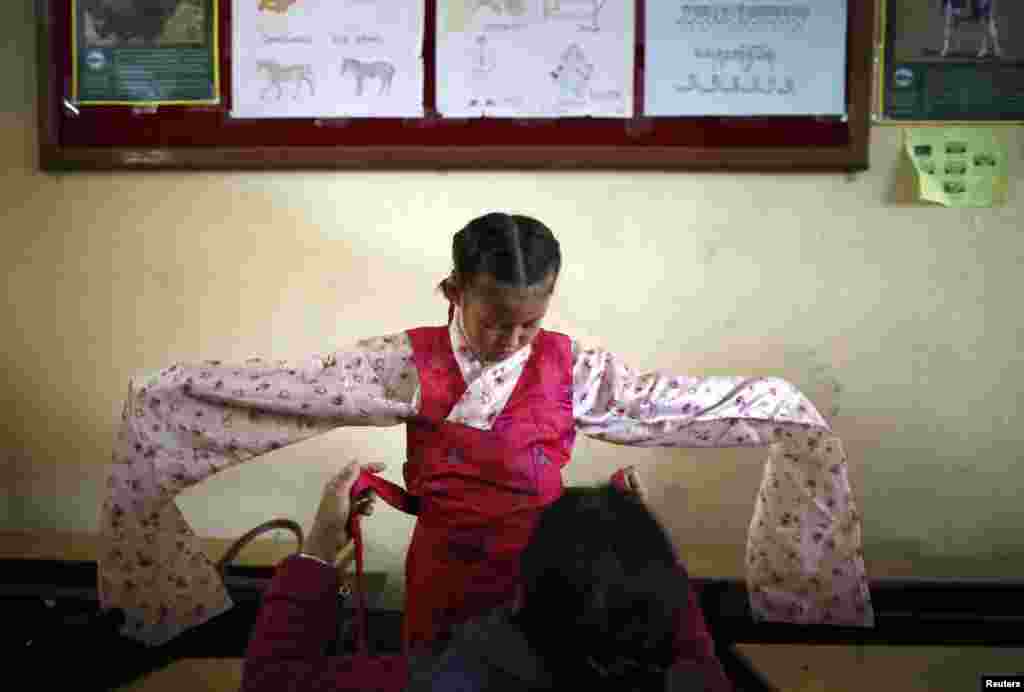 네팔의 티베트 망명 가정 어린이가 티베트의 정신적 지도자 달라이 라마의 노벨평화상 수상 25주년을 축하하는 행사에 참석하기 위해 전총 복장을 입고 있다.