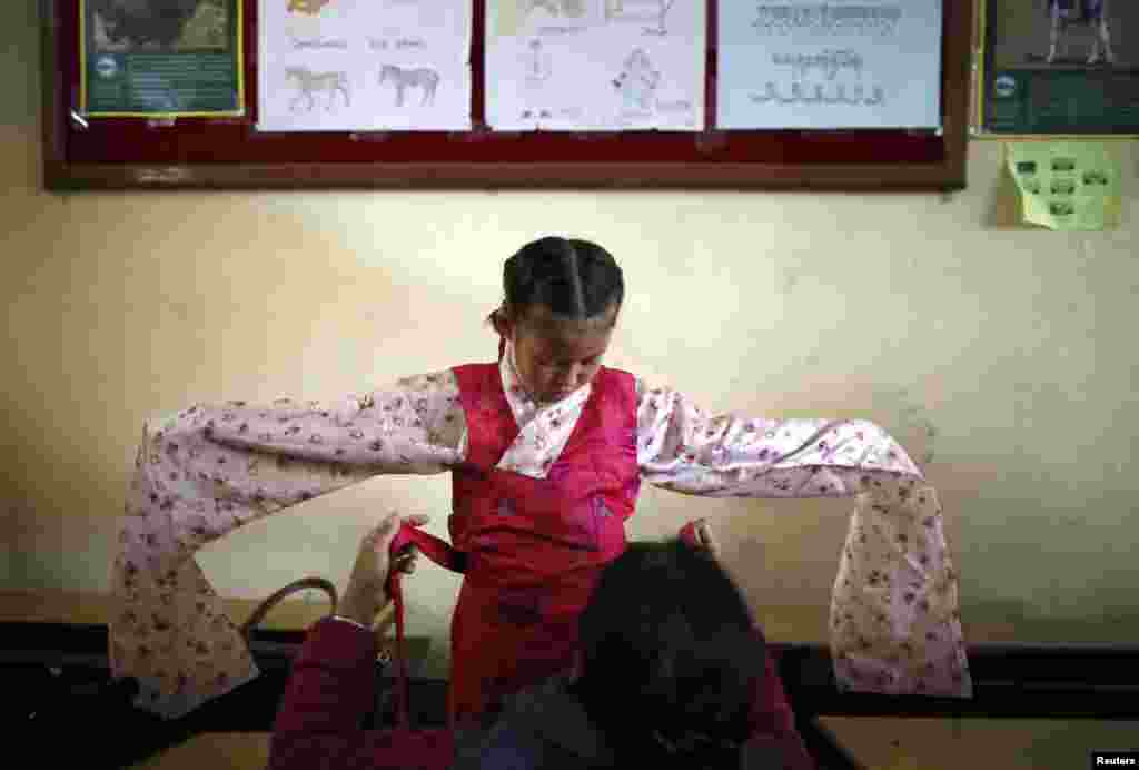 A Tibetan girl gets help from her mother as she gets dressed for an event organized by the Tibetan Refugee Community in Nepal commemorating the 25th Anniversary of the Nobel Peace Prize to exiled Tibetan spiritual leader Dalai Lama and the 66th International Human Rights Day in Kathmandu, Nepal.