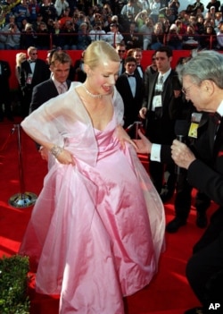 British actress Gwyneth Paltrow lifts the hem of her skirt to speak to a television reporter as she arrives for the 71st annual Academy Awards ceremony, March 21, 1999, in Los Angeles.