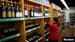 A staff checks on bottles of wine at a supermarket in Shanghai, China, June 2, 2016. 