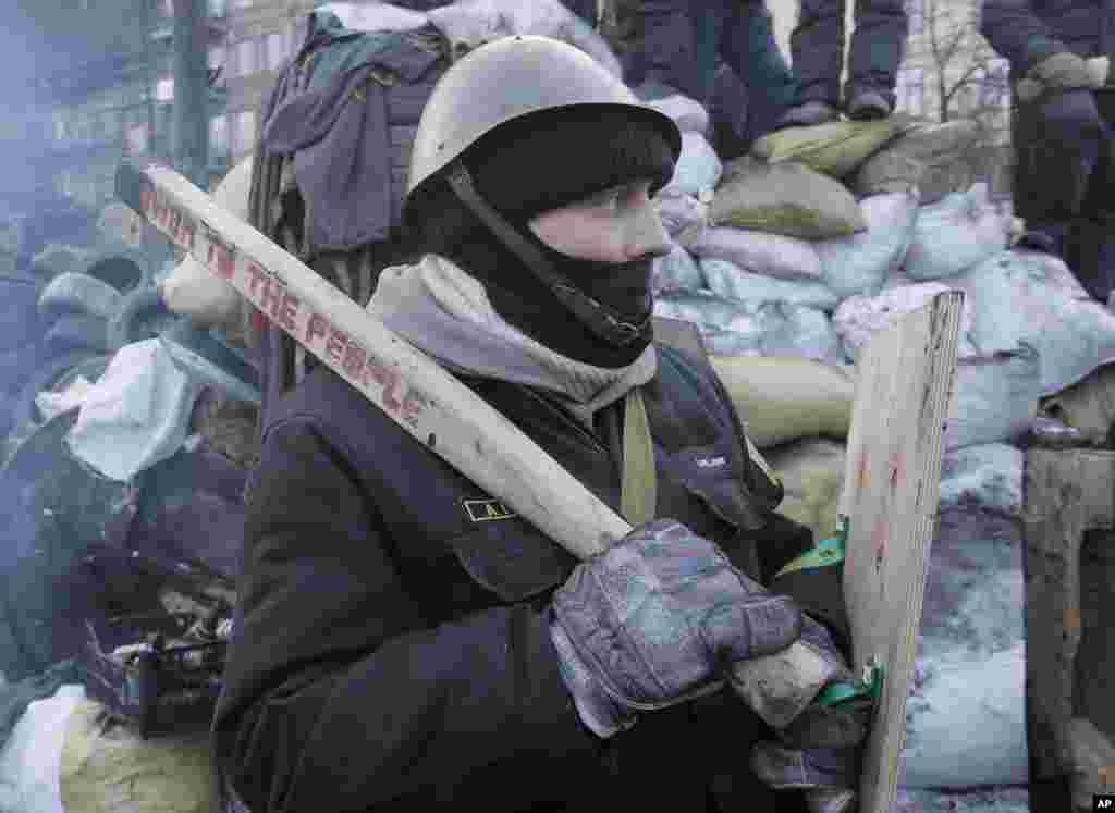 A protester stands guard at the barricades in front of riot police in Kyiv, Jan. 27, 2014. 