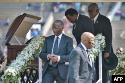 Former Democratic Republic of the Congo President Joseph Kabila (back, 2ndR) bows on September 14, 2019 as he says a final farewell at the casket of late Zimbabwean President Robert Mugabe, behind former South African President Thabo Mbeki (L)
