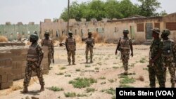 FILE - Soldiers walk among the ruins of the Government Secondary School in Chibok, Nigeria, March 25, 2016.