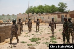 Soldiers walk among the ruins of the Government Secondary School in Chibok, Nigeria, March 25, 2016.