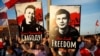 FILE - Supporters hold up placards of jailed Belarusian journalists and bloggers Raman Pratasevich and Ihar Losik, calling for their release, at a rally in Warsaw, Poland, June 3, 2021.