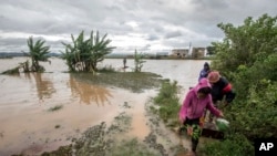 Workers take a makeshift boat to cross flooded vegetable gardens in Madagascar's capital Antananarivo, March 9, 2017. 