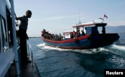 FILE - Police guard a wooden boat carrying ethnic Rohingya refugees from Myanmar. Australian officials say their policies have prevented asylum seekers from risking their lives at sea trying to reach Australia by boat.