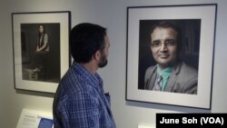 Tara Dhungana looks at his own portrait and story, one of the 20 on display at the Ohio History Center. Dhungana is now a restaurant owner in Columbus, and he sees the exhibit as a way to recapture some of the history his people have lost.