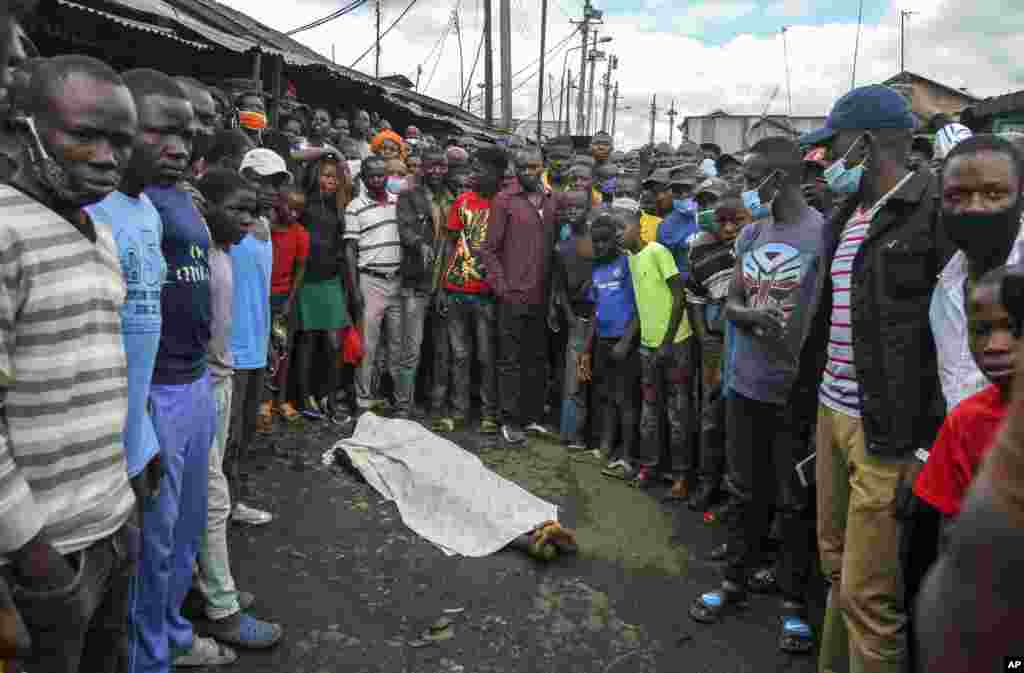 Residents gather around the covered dead body of a man, who they claimed had been beaten by police for being outside during the dusk to dawn curfew, but which could not be independently verified, in the Mathare slum, or informal settlement, of Nairobi, Kenya.