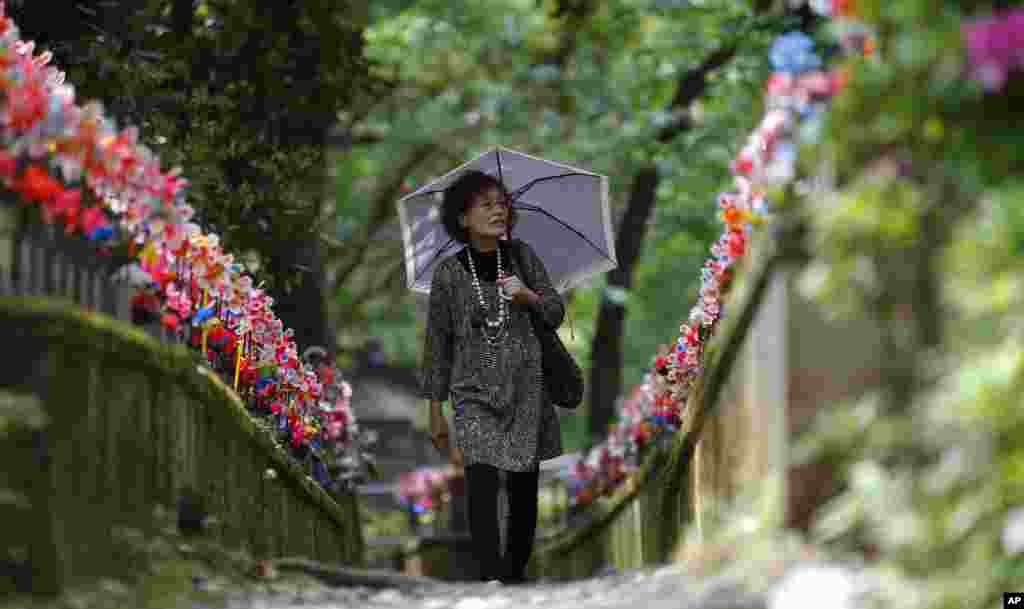Seorang perempuan berjalan sepanjang barisan patung-patung batu &quot;jizo&quot; merepresentasikan anak-anak yang belum lahir di kuil Buddha Zojoji di Tokyo. Jizo, yang merupakan tokoh paling dicintai dalam keyakinan Buddha Jepang, dipercaya melindungi anak-anak yang sudah meninggal.