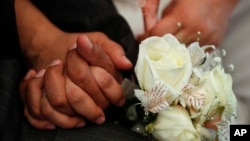 FILE - Newlyweds holds hands during a mass wedding ceremony.