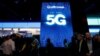 FILE - People walk by a video display promoting 5G connectivity at the Qualcomm booth during the 2019 CES in Las Vegas, Nevada, Jan. 8, 2019.