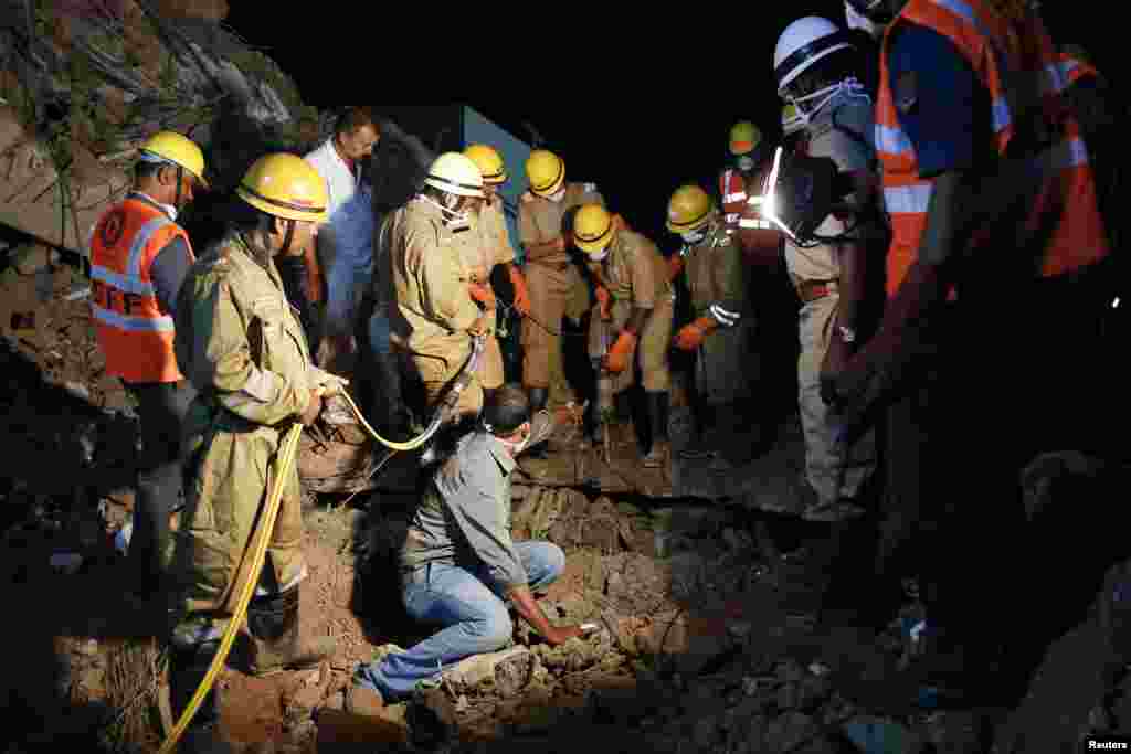 Rescue workers attempt to remove the body of a victim at the site of a collapsed building that was under construction, Canacona, India, Jan. 5, 2014.