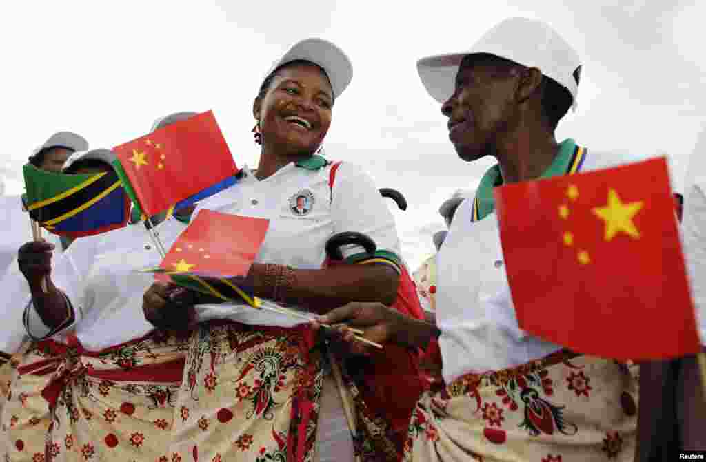 Tanzanian women wait for China's President Xi Jinping to arrive at Julius Nyerere International Airport in Dar es Salaam, March 24, 2013. 