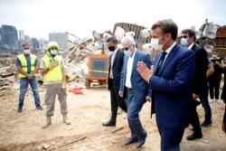 Presiden Perancis Emmanuel Macron (kanan) memberikan salam dengan isyarat tangannya kepada regu penyelamat setibanya di lokasi ledakan di pelabuhan Beirut, Lebanon, Kamis 6 Agustus 2020.