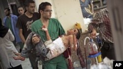 A doctor carries a severely wounded Syrian boy in the Dar El Shifa hospital, in Aleppo, Syria, Oct. 4, 2012 after the child was hit by Syrian Army shelling. 