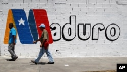 Supporters of Venezuela's President Nicolas Maduro walk past a campaign mural before a rally with him, in Charallave, Venezuela, May 15, 2018.