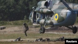FILE - Members of the National Guard of Ukraine jump out a MI-8 helicopter during military tactical exercises at a training base near Kiev, Ukraine, July 22, 2015.