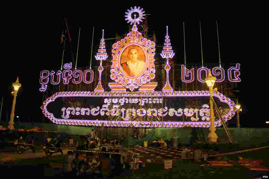 ការរៀបចំតុបតែងលម្អនៅមុខព្រះបរមរាជវាំងក្នុងរាជធានីភ្នំពេញ ដើម្បីអបអរថ្វាយព្រះពរខួបទី១០នៃព្រះរាជពិធីគ្រងរាជសម្បត្តិរបស់ព្រះបាទសម្ដេចព្រះបរមនាថ នរោត្តម សីហមុនី នៅថ្ងៃទី ២៦ ខែតុលា ឆ្នាំ២០១៤។ (នូវ ពៅលក្ខិណាVOA)