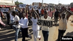Hundreds of protesters, some carrying placards, chanted anti-government slogans before clashing with riot policemen in Burundi's capital, Bujumbura, April 28, 2015.
