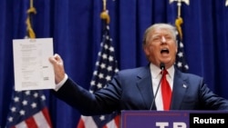 U.S. Republican presidential candidate, real estate mogul and TV personality Donald Trump holds up his financial statement showing his net worth as he formally announces his campaign for the 2016 Republican presidential nomination in New York, June 16, 20