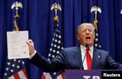 U.S. Republican presidential candidate, real estate mogul and TV personality Donald Trump holds up his financial statement showing his net worth as he formally announces his campaign for the 2016 Republican presidential nomination in New York, June 16, 2015.