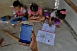 Murid-murid SD di desa Bukit Temulawak, Yogyakarta belajar secara online menggunakan ponsel pintar yang dipakai bersama. (Foto: AFP)