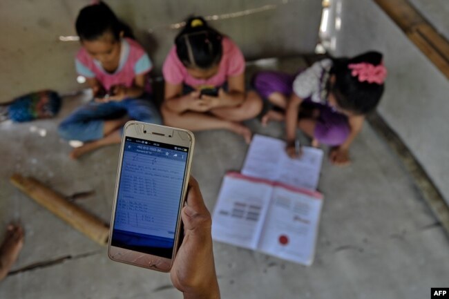 Murid-murid SD di desa Bukit Temulawak, Yogyakarta belajar secara online menggunakan ponsel pintar yang dipakai bersama. (Foto: AFP)