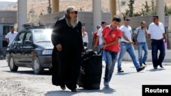 Syrian people carry their belongings as they enter Turkey with their family from the Turkish Cilvegozu border gate, located opposite Syrian commercial crossing point Bab al-Hawa in Reyhanli, Hatay province, Sept. 4, 2013.