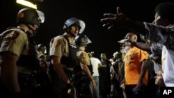 FILE - Officers and protesters face off along West Florissant Avenue in Ferguson, Mo., Aug. 10, 2015. The city released details Wednesday of a tentative deal with the U.S. Justice Department to reform its police department.