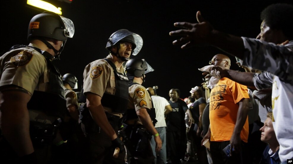 FILE - Officers and protesters face off along West Florissant Avenue in Ferguson, Mo., Aug. 10, 2015. The city released details Wednesday of a tentative deal with the U.S. Justice Department to reform its police department.