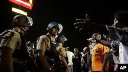 FILE - Officers and protesters face off along West Florissant Avenue in Ferguson, Mo., Aug. 10, 2015. The city released details Wednesday of a tentative deal with the U.S. Justice Department to reform its police department.