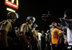 FILE - Officers and protesters face off along West Florissant Avenue in Ferguson, Missouri, Aug. 10, 2015.