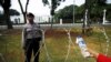 FILE - An Indonesian street vendor offers water to a policeman as he guards in front of the Presidential Palace in Jakarta, Oct. 15, 2015. 