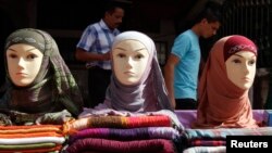 FILE - Men walk past mannequins modelling veils in Tripoli.