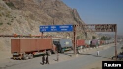 Beberapa orang pria berjalan di dekat papan penunjuk jalan yang menunjukkan jarak menuju beberapa kota di Afghanistan, saat sebuah truk melintasi perbatasan kota Torkham, perlintasan perbatasan Afghanistan-Pakistan (foto: dok). 