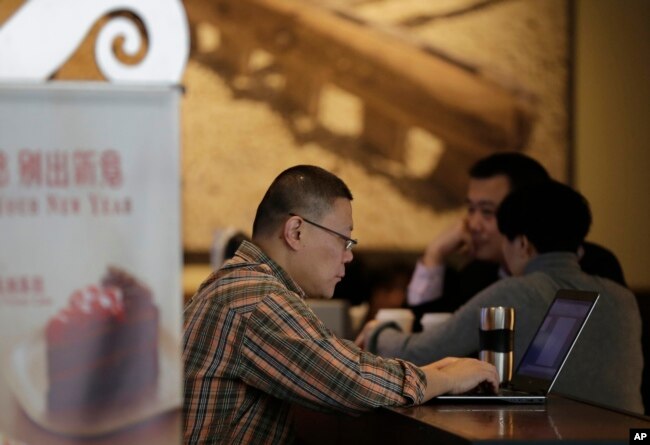 FILE - A man surfs Internet on his laptop computer at a Starbucks cafe in Beijing, Feb. 16, 2015.