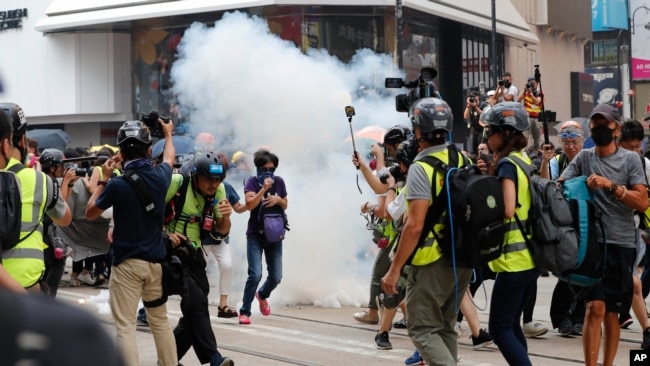 Un grupo de manifestantes corre después que la policía les lanzó gas lacrimógeno en el distrito comercial deHong Kong, cuando se negaron a dispersarse. Domingo 29 de septiembre de 2019.